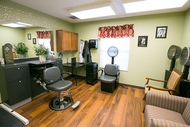A cozy hair salon interior with a barber chair, hair dryer, and waiting area.