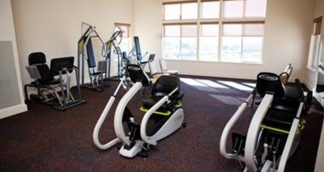 A well-lit gym with various exercise equipment.