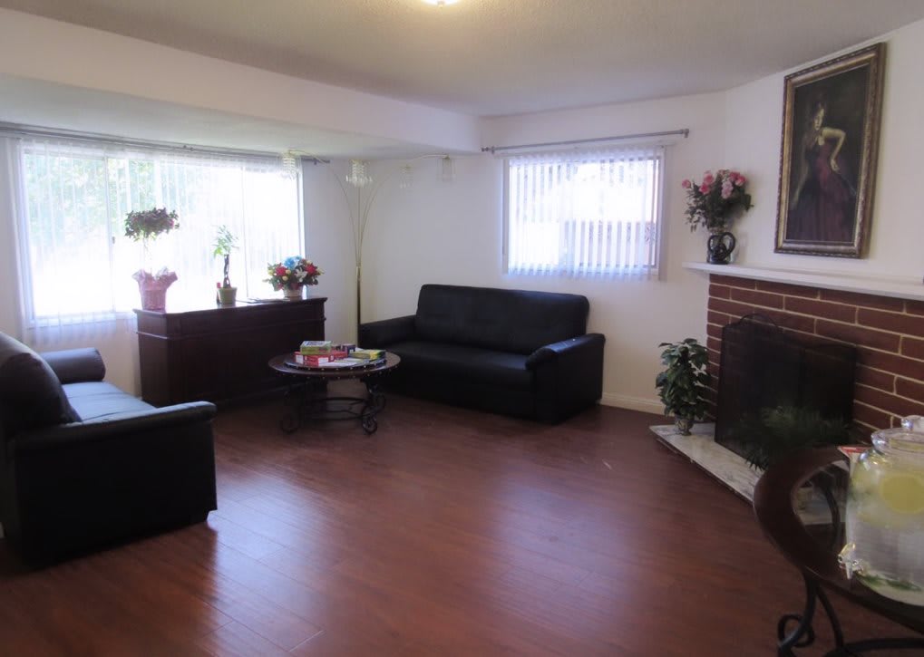 A cozy living room with dark sofas, a coffee table, and a fireplace.