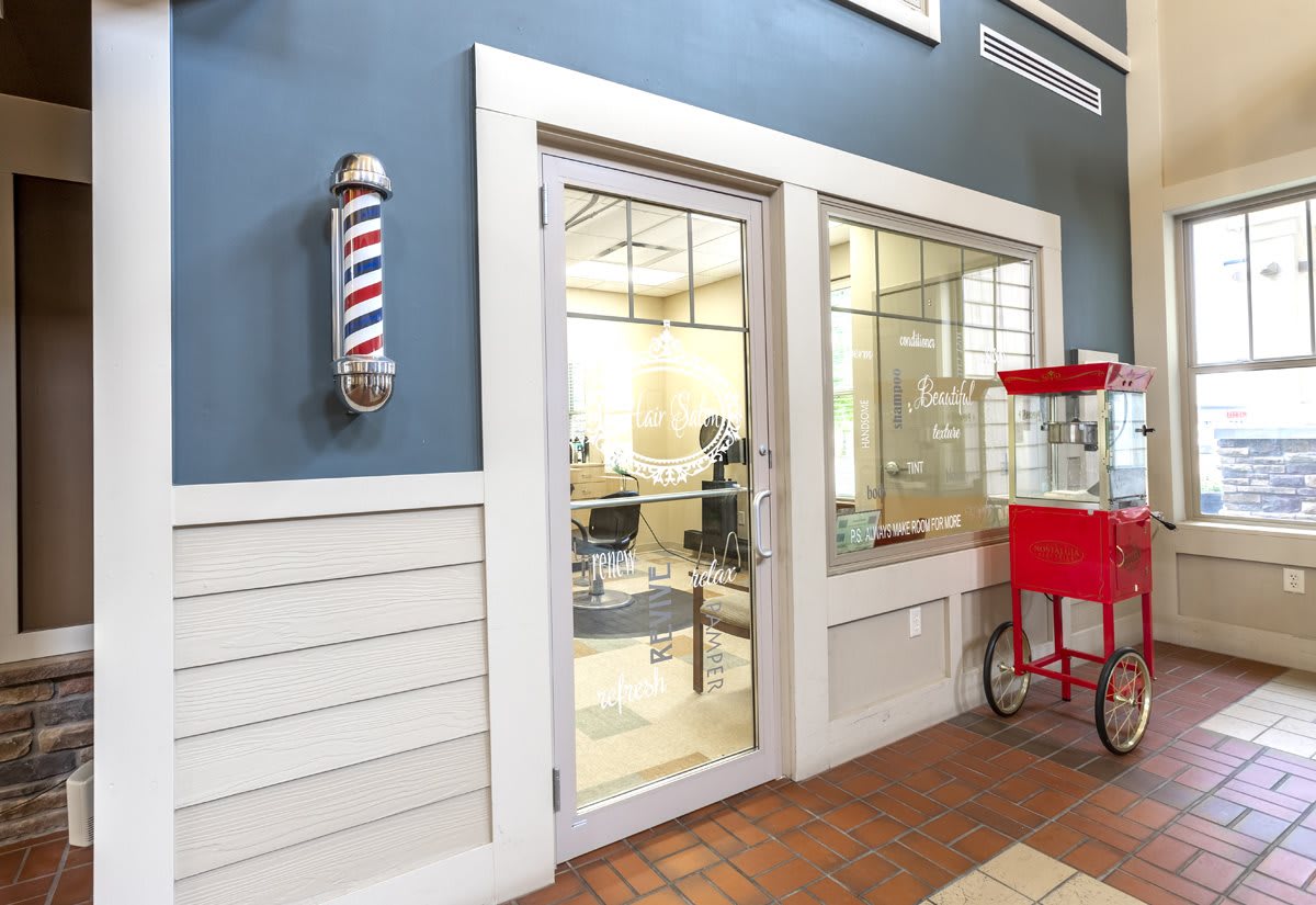 A cozy barbershop with a classic barber pole and a popcorn machine outside.