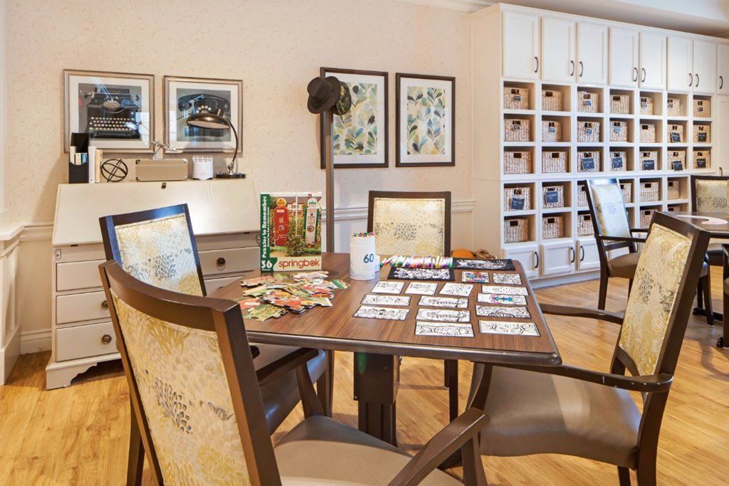 A cozy game room with a table set up for solving puzzles, surrounded by comfortable chairs and decorated with artwork on the walls.