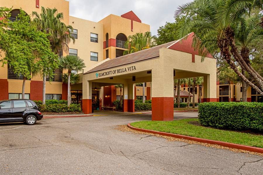 A welcoming entrance to a multi-story building surrounded by greenery.