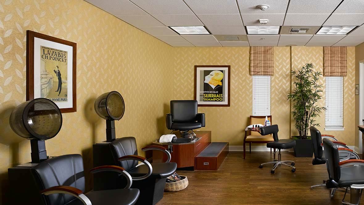 A cozy salon waiting area with a hair dryer, chairs, and a TV.