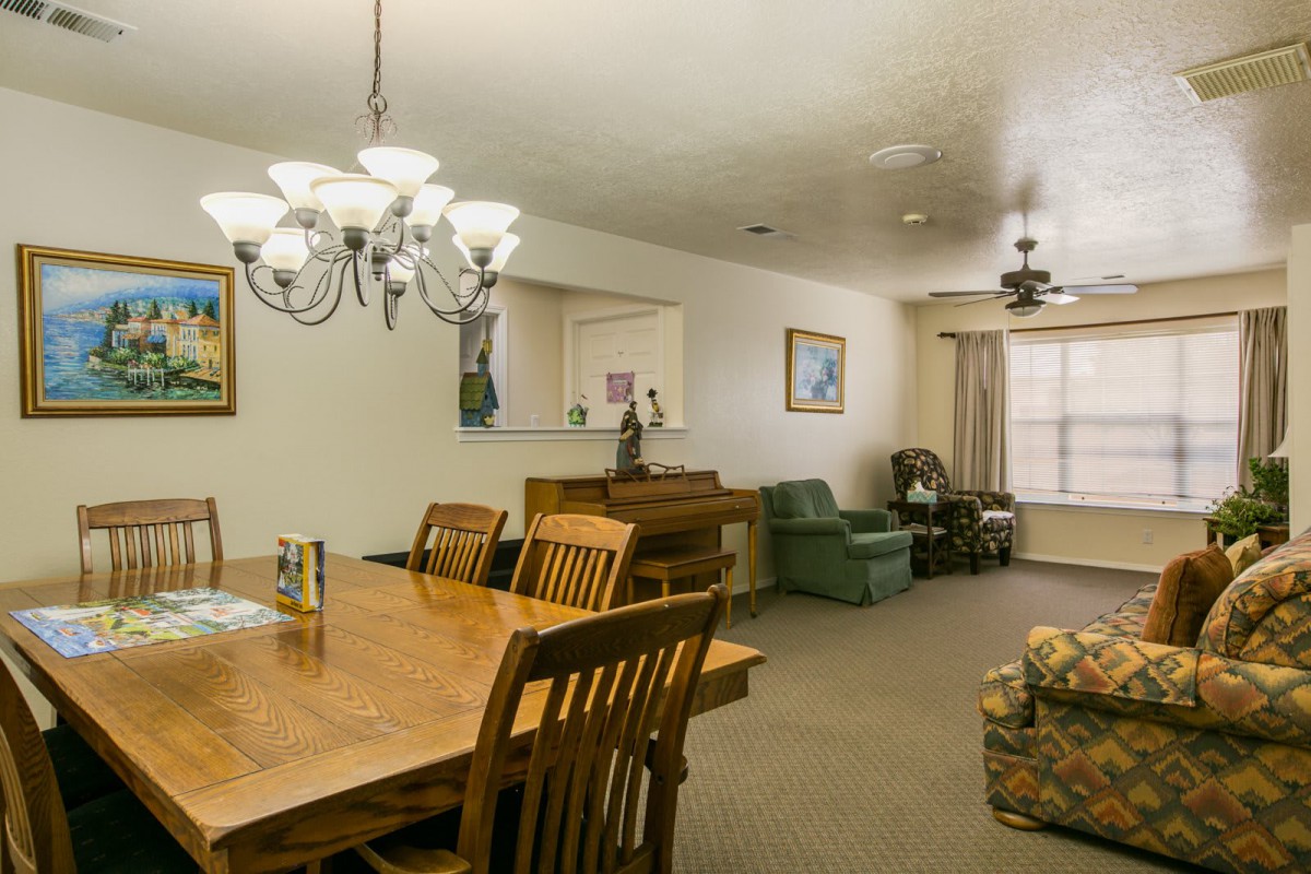 A cozy dining and living area featuring a wooden dining table with chairs, a chandelier, and a comfortable seating arrangement.