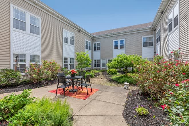 A peaceful courtyard with outdoor seating and lush greenery between residential buildings.