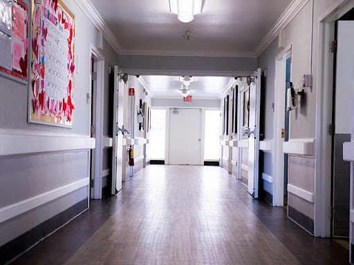 A quiet hospital hallway with doors leading to patient rooms.