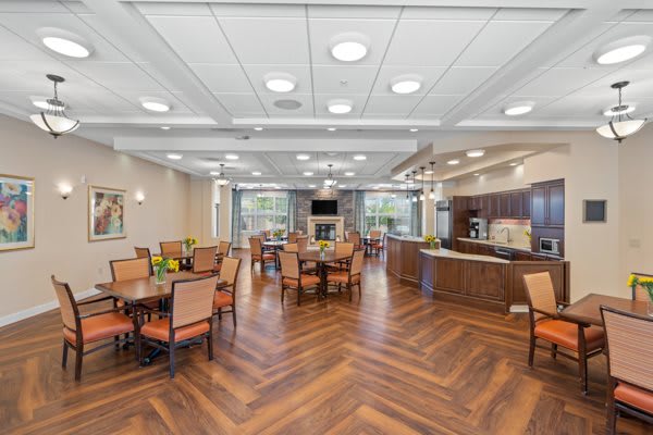 A modern dining area with several tables and chairs, featuring a wooden floor and bright lighting.
