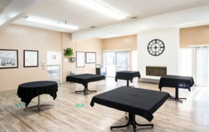A modern interior room with tables covered in black tablecloths and a large clock on the wall.