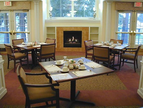 A cozy dining room with neatly set tables and a fireplace.