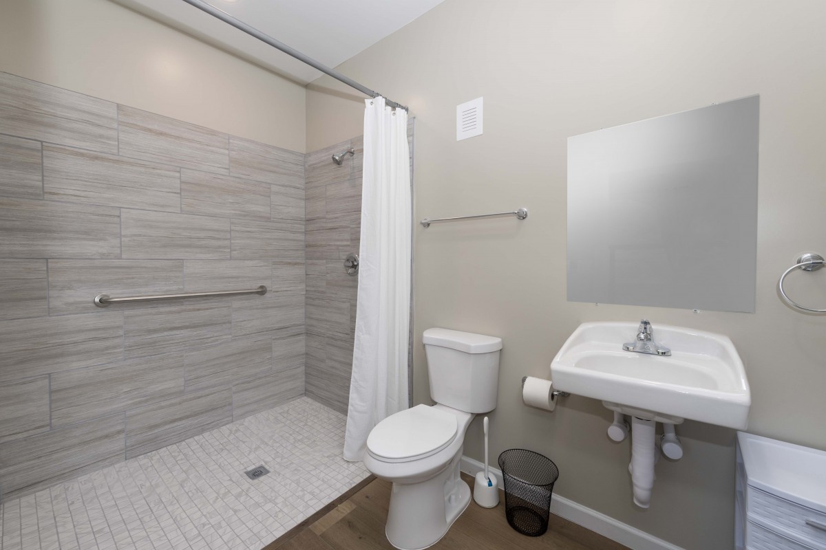 A modern bathroom with a walk-in shower, toilet, and sink.