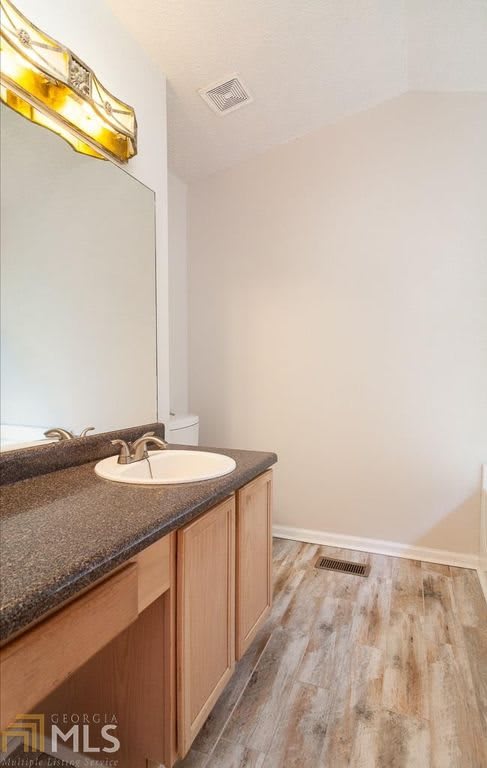 A modern bathroom with a sink, mirror, and wooden cabinets.