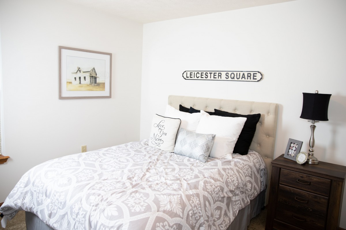 A minimalist bedroom with a neatly made bed and wall art.