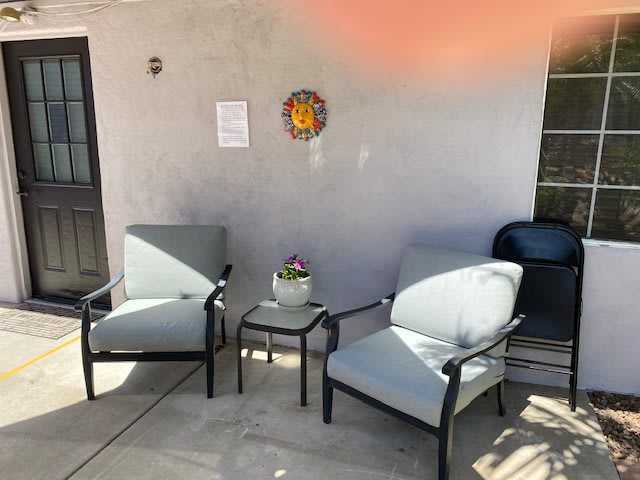 A cozy patio setup with two chairs, a small table, and decorative wall hanging.
