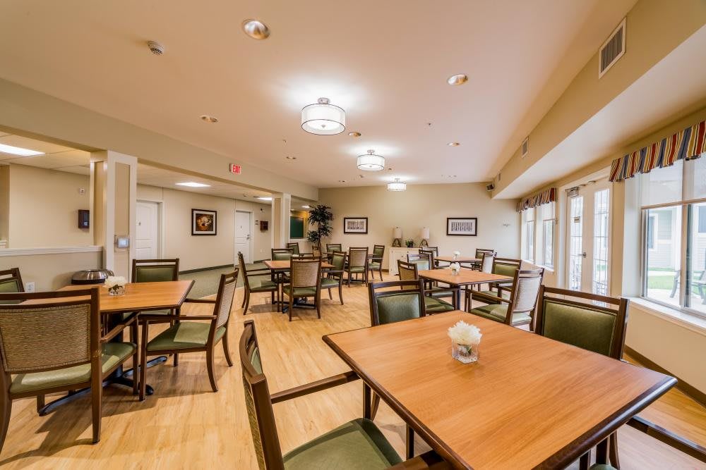 A spacious dining room with neatly arranged tables and chairs, well-lit with overhead lighting.