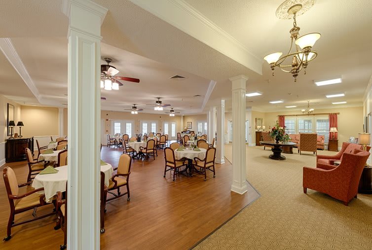 An elegantly designed dining room with multiple tables and chairs, featuring warm lighting and wooden flooring.
