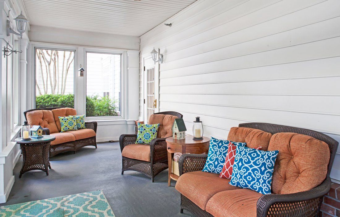 A cozy indoor porch with comfortable seating and colorful cushions.