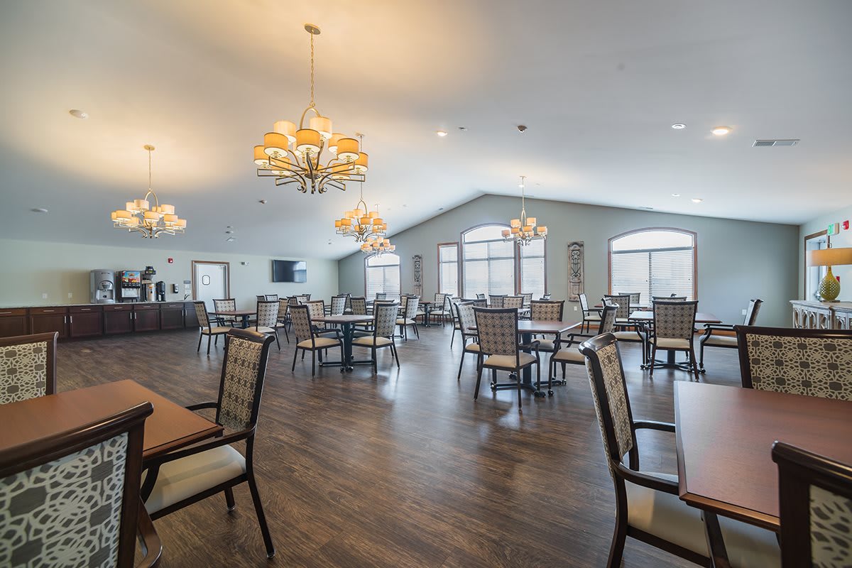 A spacious dining area with elegant chandeliers and neatly arranged tables and chairs.