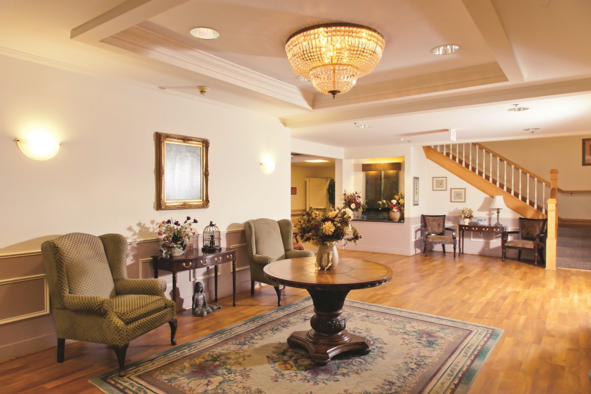 A cozy lobby area with elegant furnishings and a central table beneath a chandelier.
