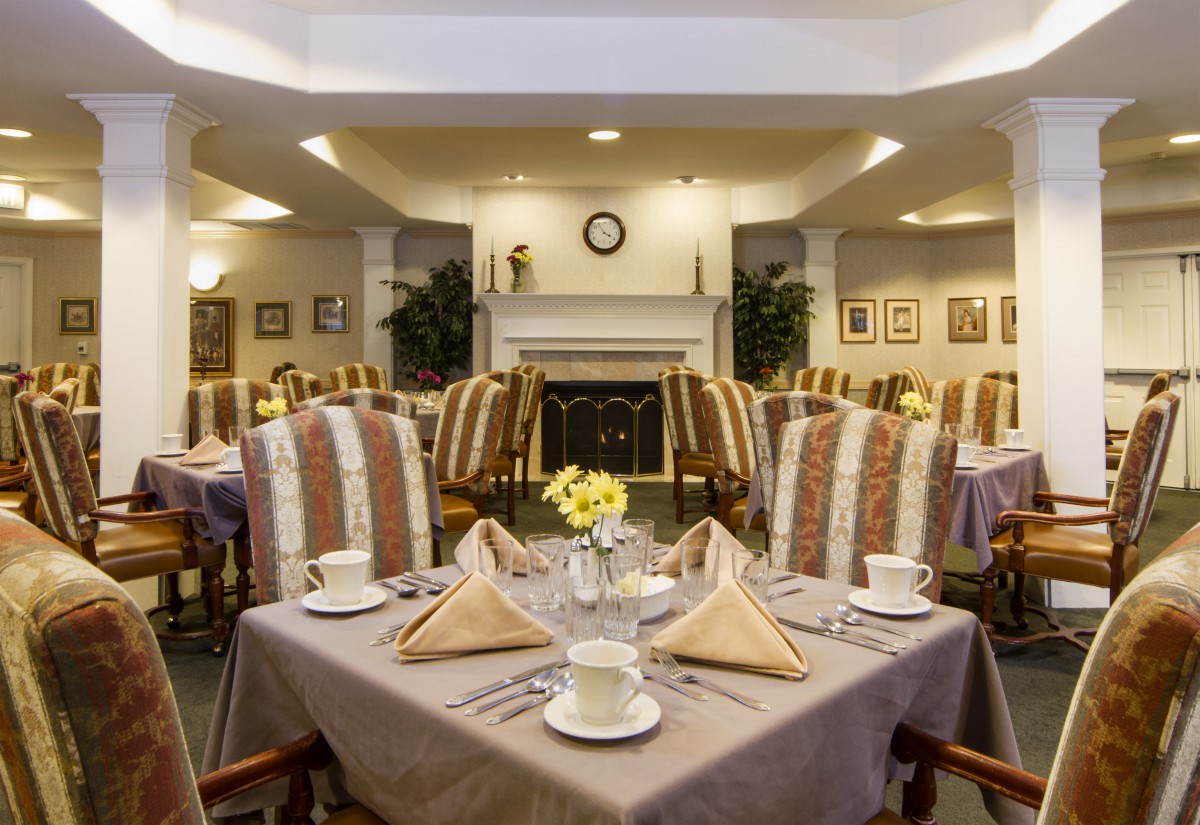 An elegantly set dining room with neatly arranged tables and chairs, featuring decorative napkins and fine tableware.