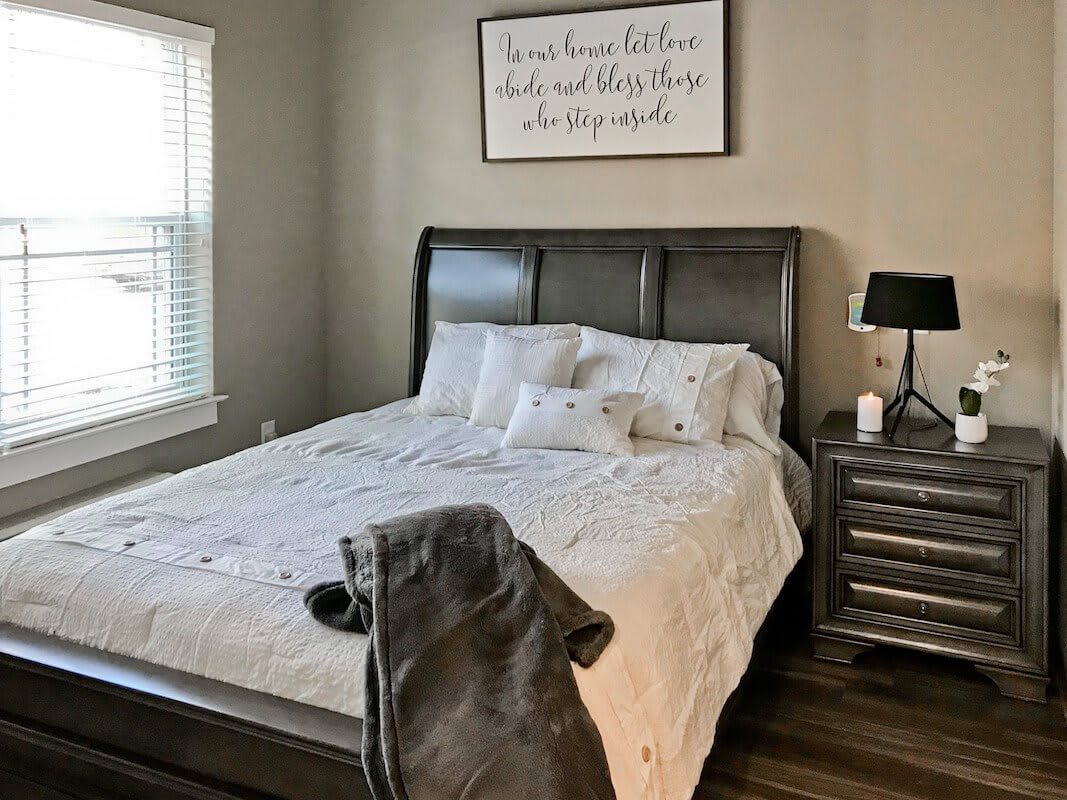 A cozy bedroom with a neatly made bed and modern furnishings.