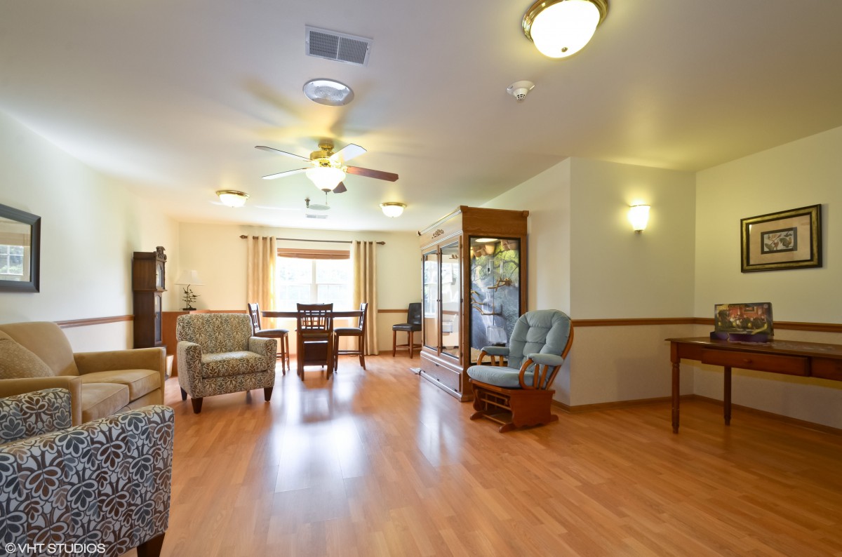 A spacious living and dining area with wooden flooring, cozy seating, and bright lighting.