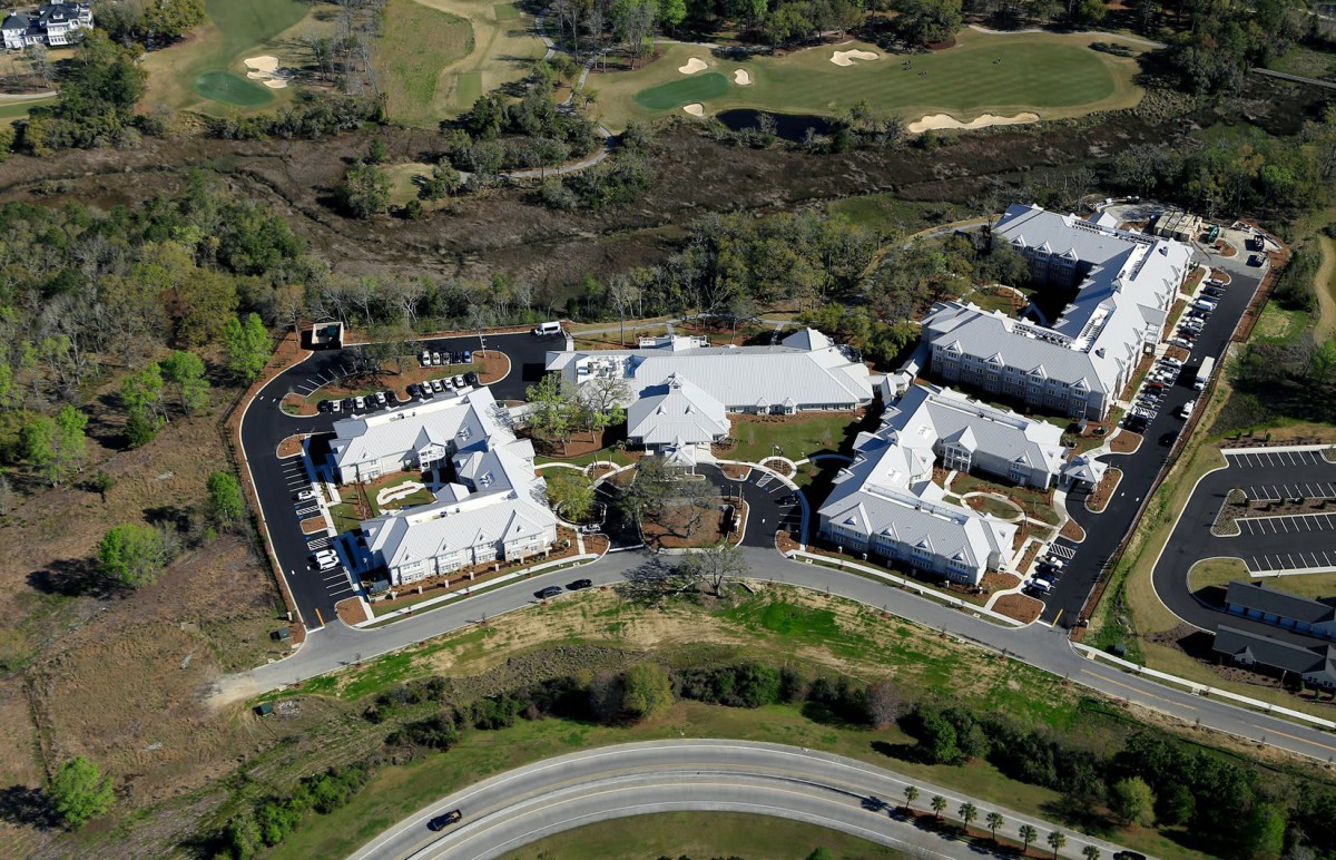 Aerial view of a residential complex with multiple buildings surrounded by roads and greenery.