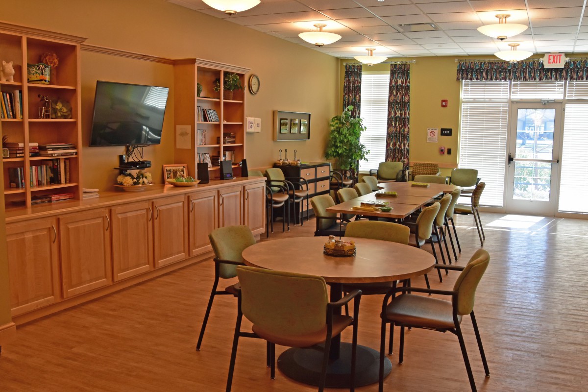 A comfortable dining area with tables and chairs, featuring a television and shelving for decor.
