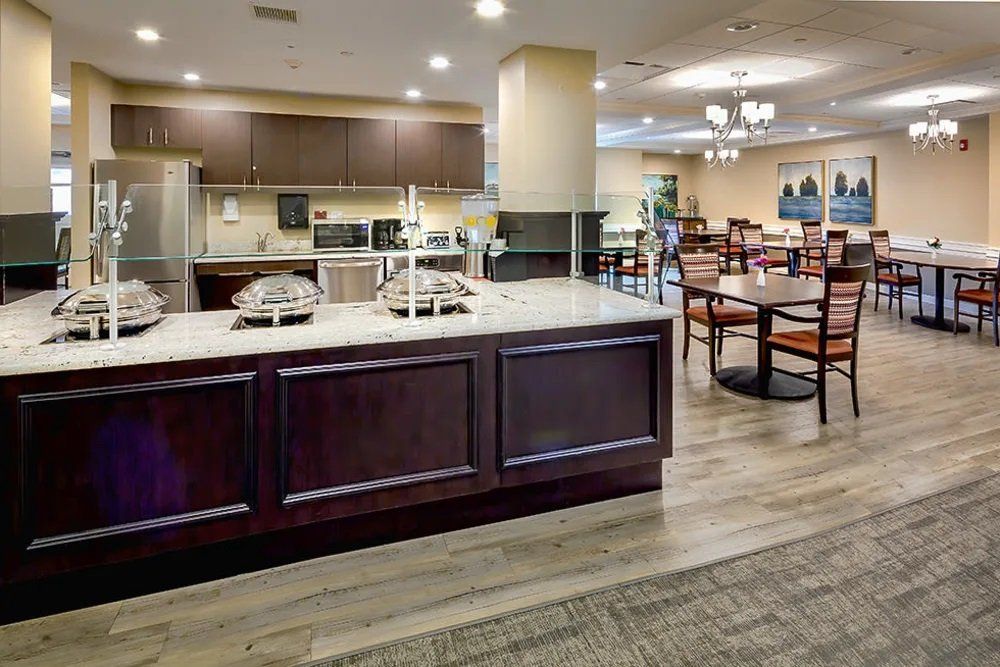 A modern dining area with a kitchen setup, featuring wooden furniture and soft lighting.