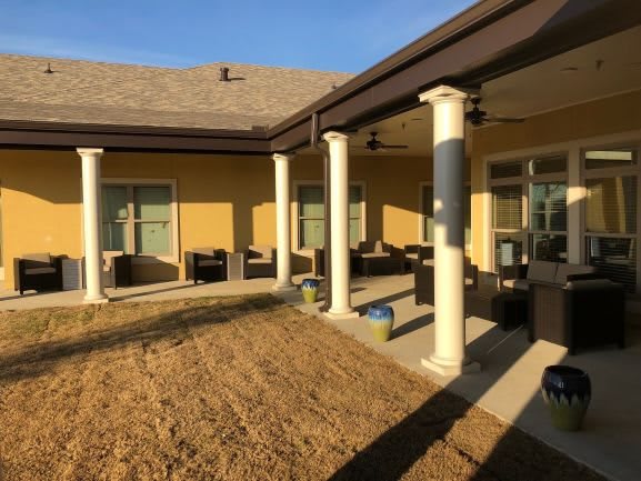 A spacious outdoor patio with comfortable seating and columns under a clear blue sky.