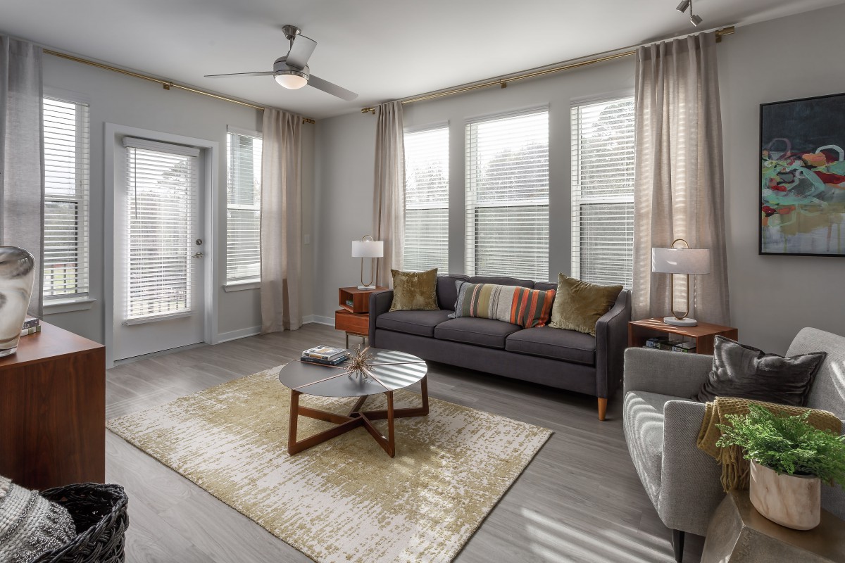 A modern living room featuring a comfortable sofa, stylish coffee table, and large windows with soft curtains.