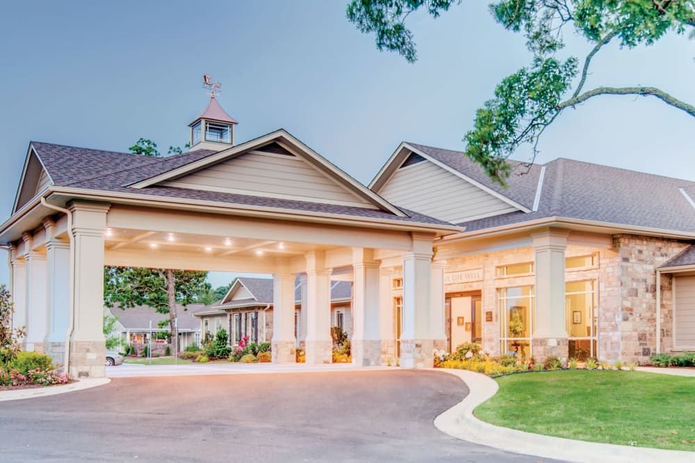 A well-lit building entrance with a covered driveway and columns.