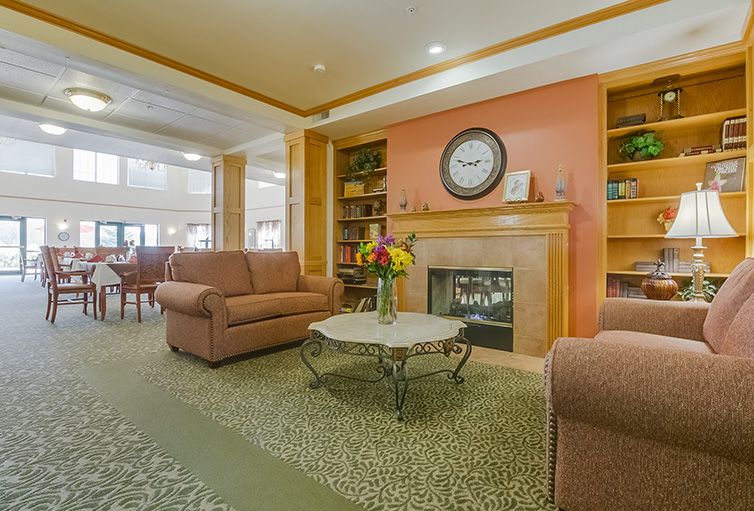 A cozy living room area with couches, a fireplace, and a decorative clock on the mantel.