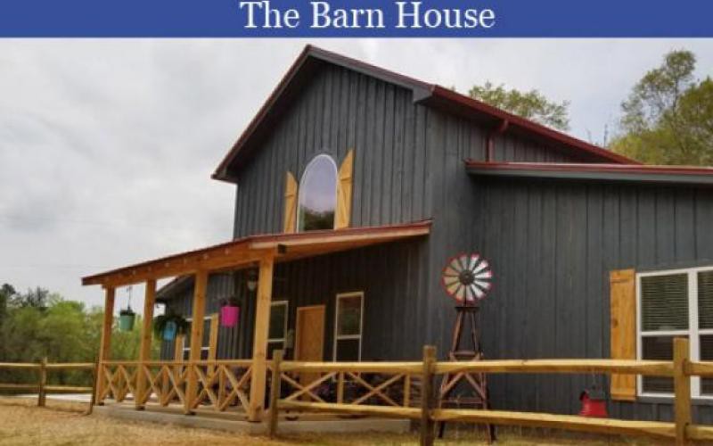 A rustic barn-style house with a porch and wooden architecture.