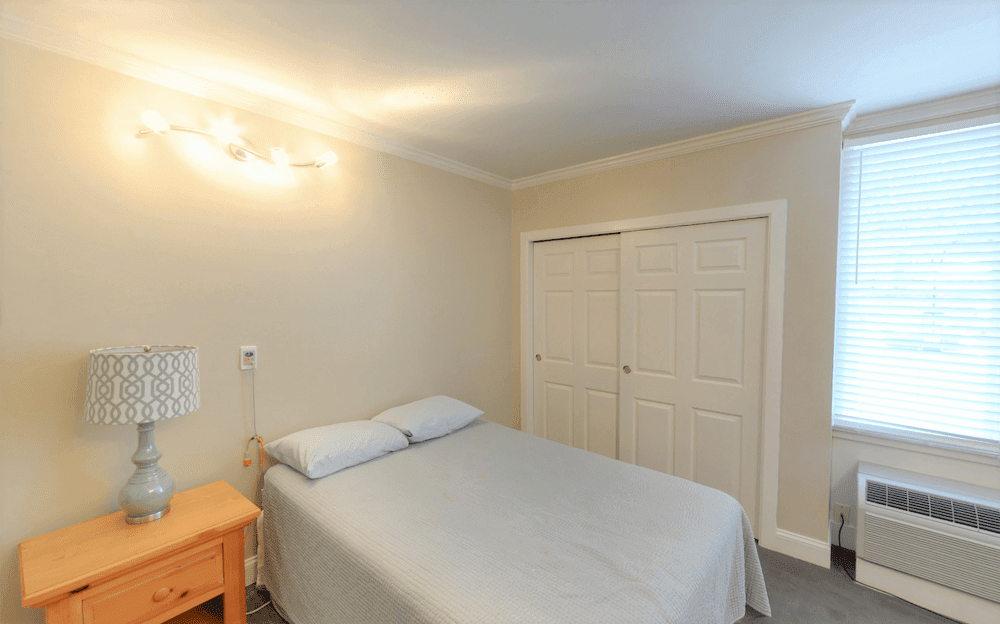 A minimalist bedroom with a bed, nightstand, and closet.