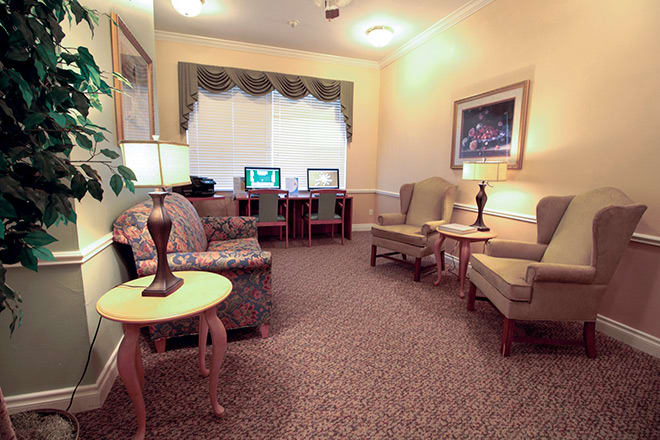 A cozy living room with comfortable seating and computer desks in a well-lit area.