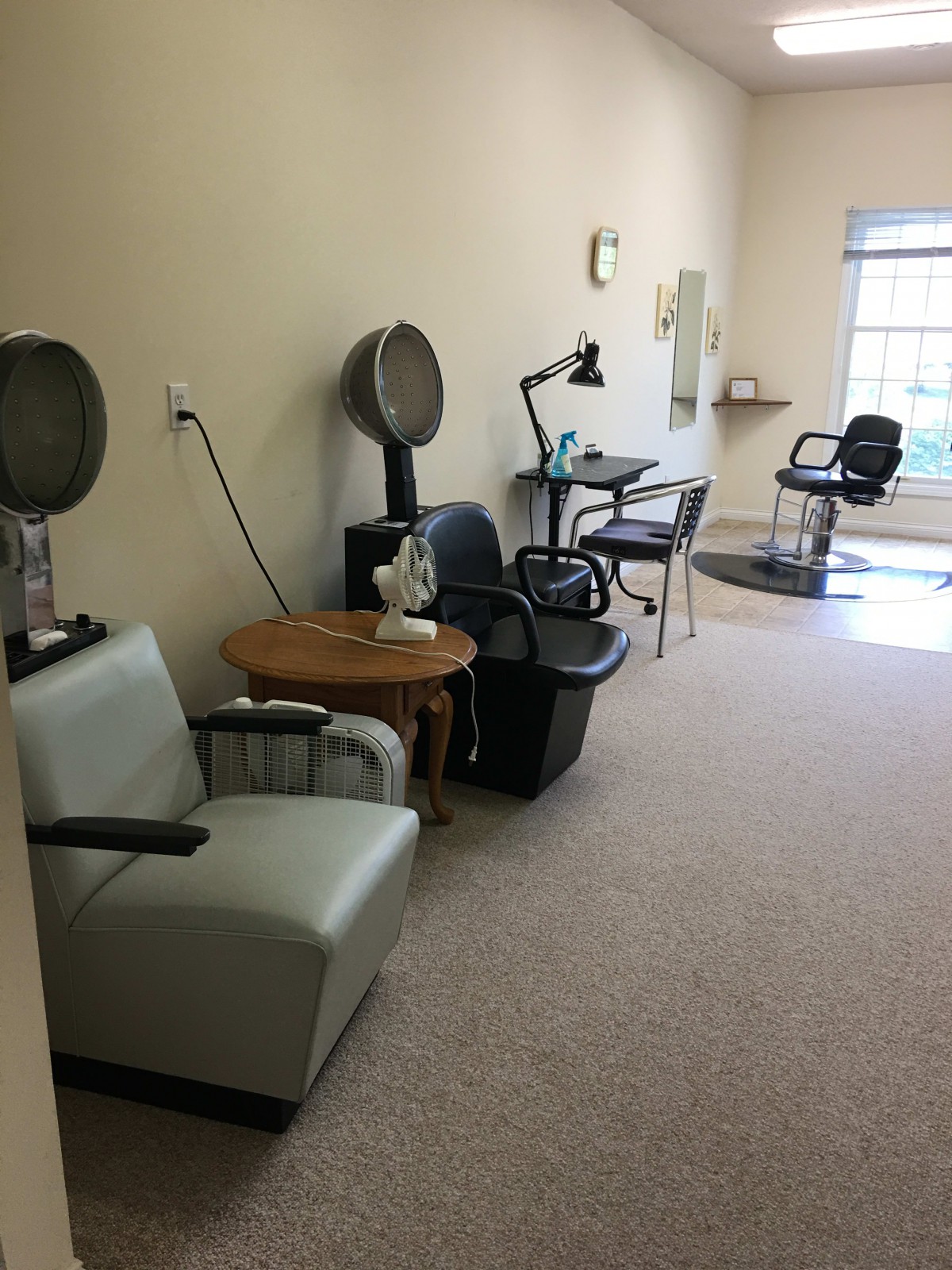 An interior view of an empty salon with hairdryers and styling chairs.