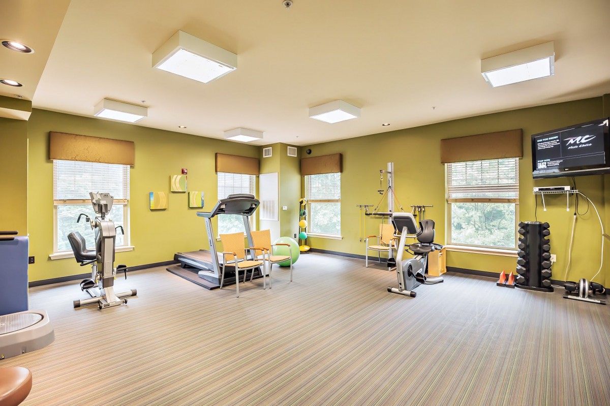 A bright and spacious gym with exercise equipment, including a treadmill and stationary bike.