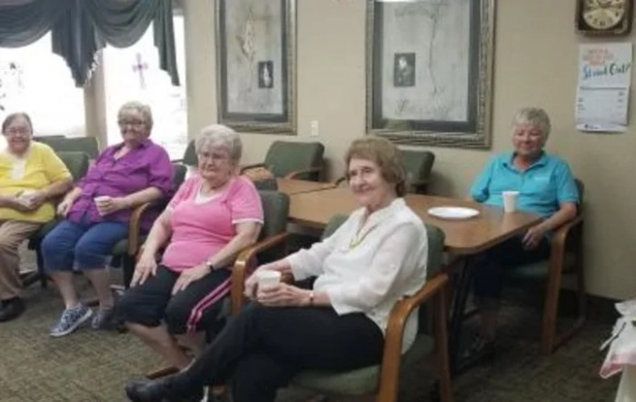 A group of elderly individuals sitting together indoors, enjoying a social gathering.