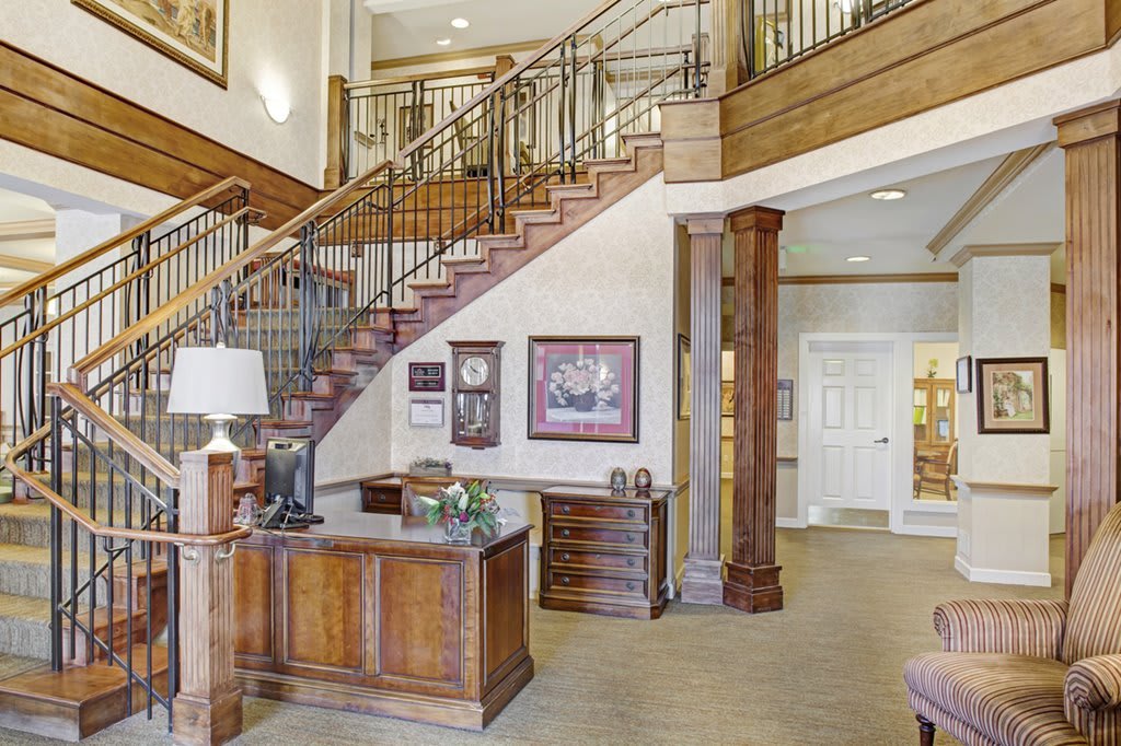 A classic interior with a grand staircase and a wooden reception desk.