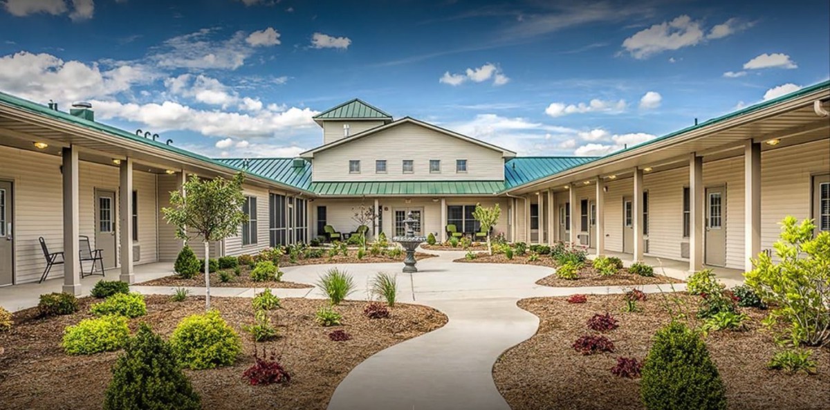 A modern building with a landscaped garden and pathway under a blue sky.