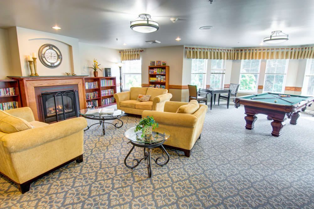 A cozy and spacious living area featuring comfortable sofas, a fireplace, and a pool table.