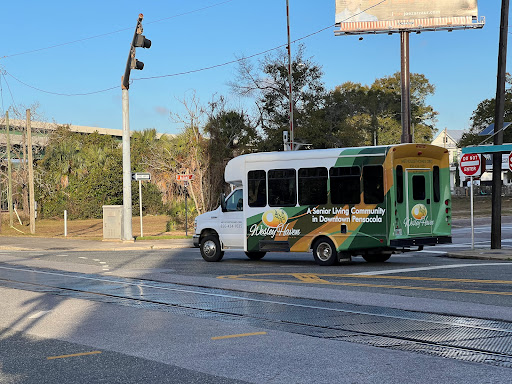 A colorful shuttle bus navigating an urban area, with a billboard in the background.