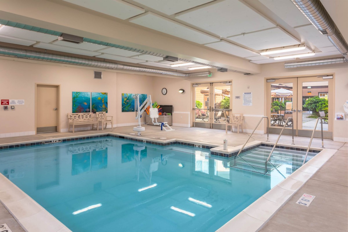 An inviting indoor swimming pool area with seating and decorative art, ideal for relaxation and recreation.
