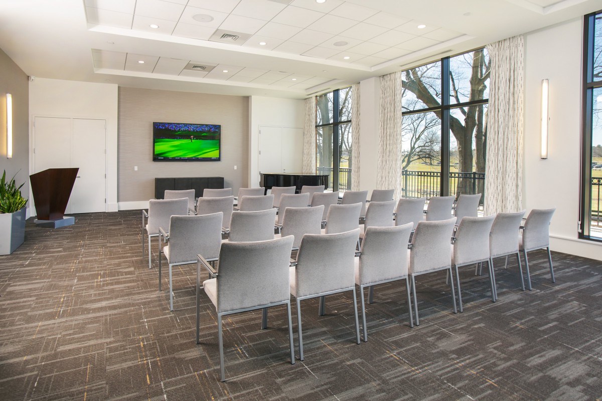 An empty conference room with rows of chairs facing a presentation screen.