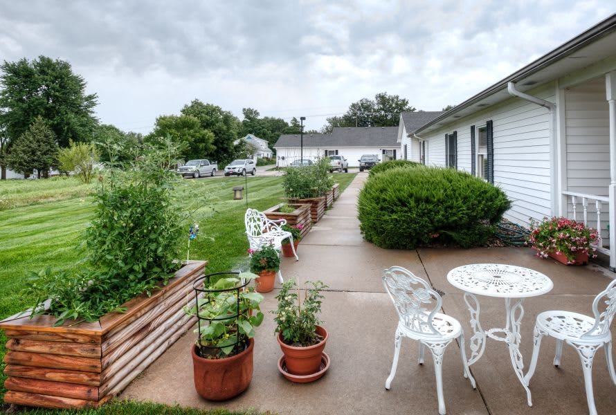 A scenic view of a garden patio with potted plants and outdoor furniture lining a walkway.