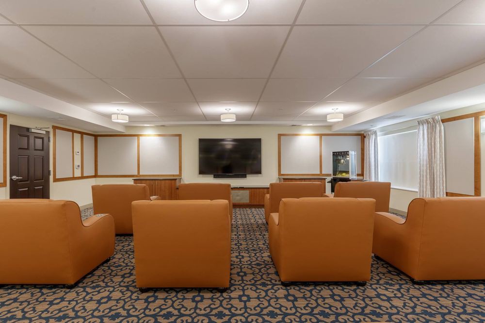 A modern lounge area with comfortable chairs facing a large television.