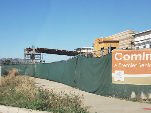 A construction site with a green fence and an informational sign.