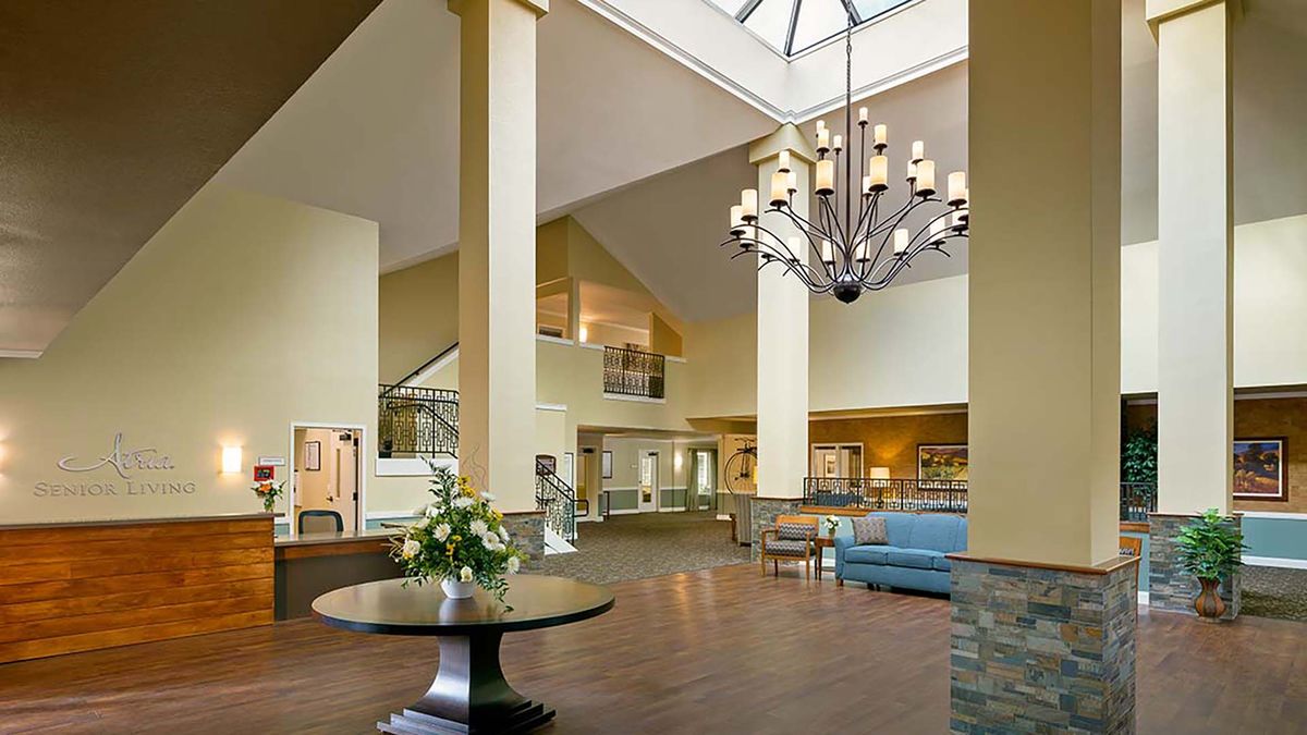 A spacious lobby featuring a large chandelier, skylight, and elegant furniture.