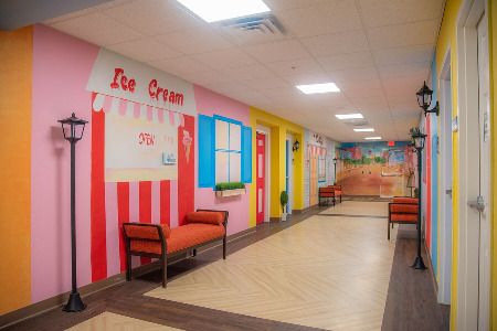 A brightly colored hallway with an ice cream shop theme and several benches along the walls.