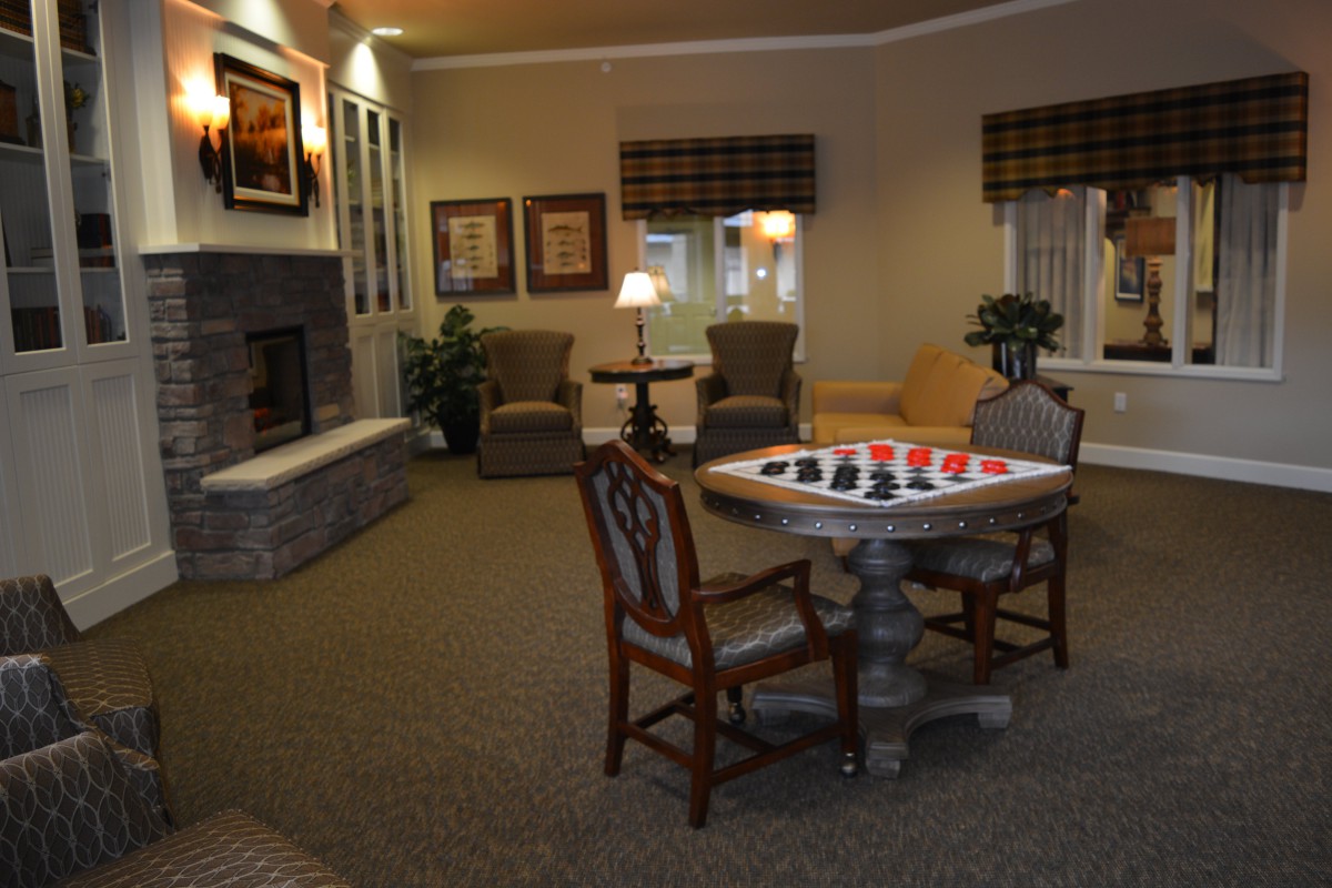 A cozy living room with a fireplace, seating area, and a table set up for chess.